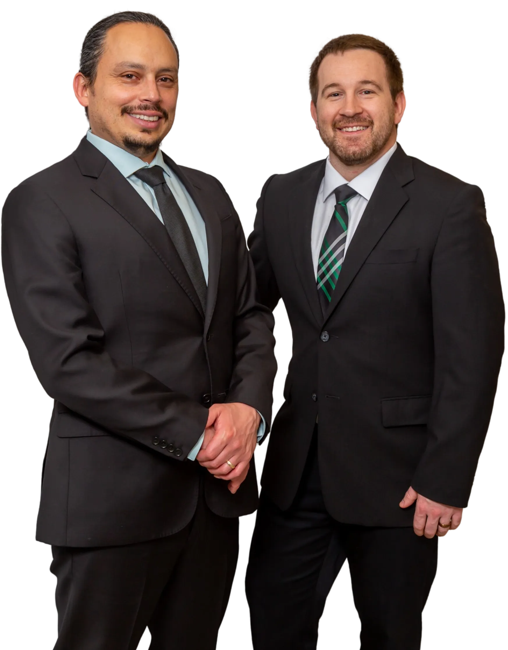 Two men in black suits smiling, one wearing a black tie and the other wearing a striped tie with green accents.